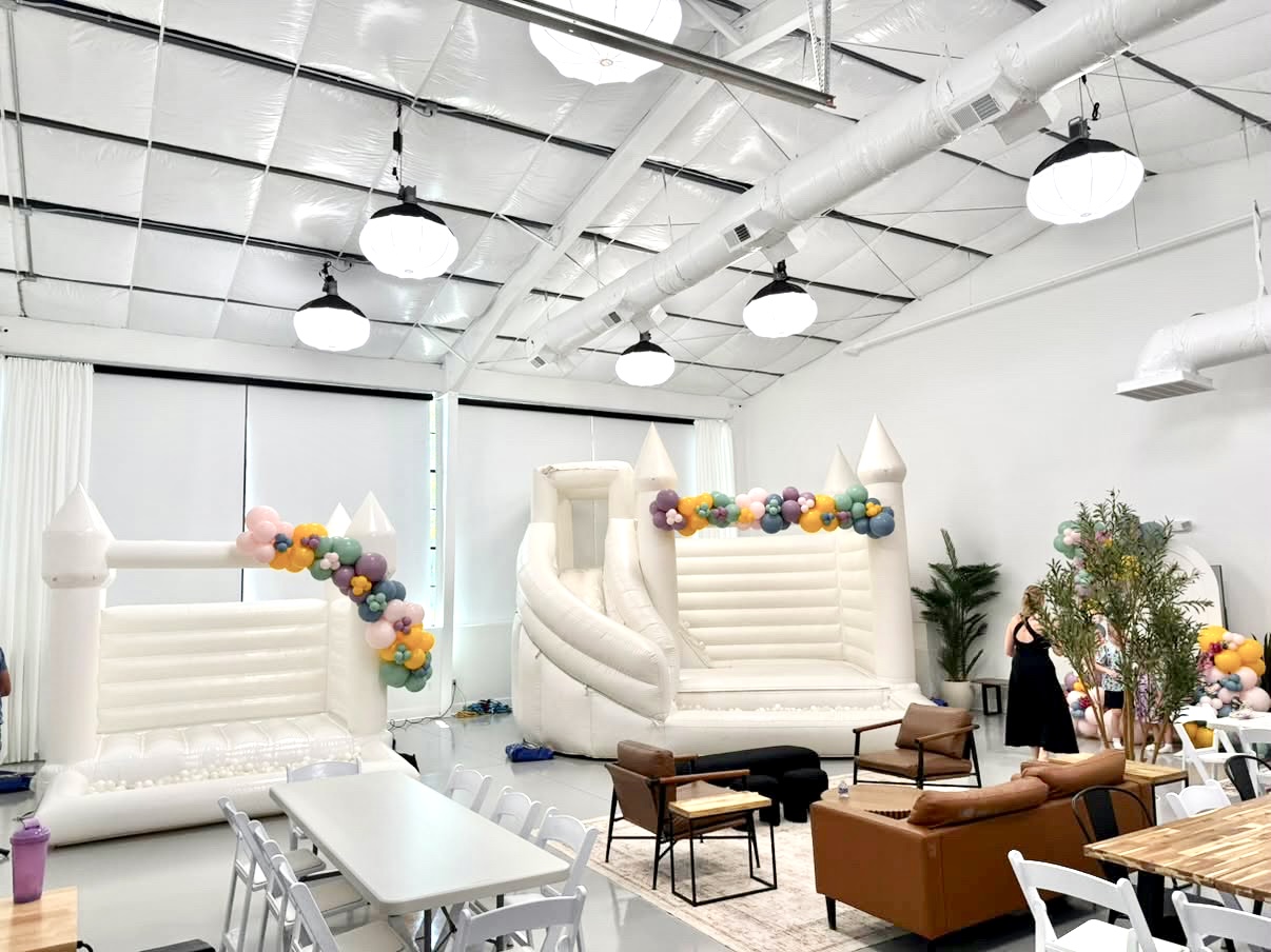 The flagship event space set up with white bounce houses, balloon garlands, and lounge seating